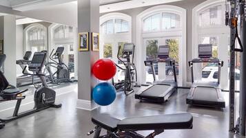 Une salle de sport équipée de tapis de course, de vélos elliptiques et de poids libres.