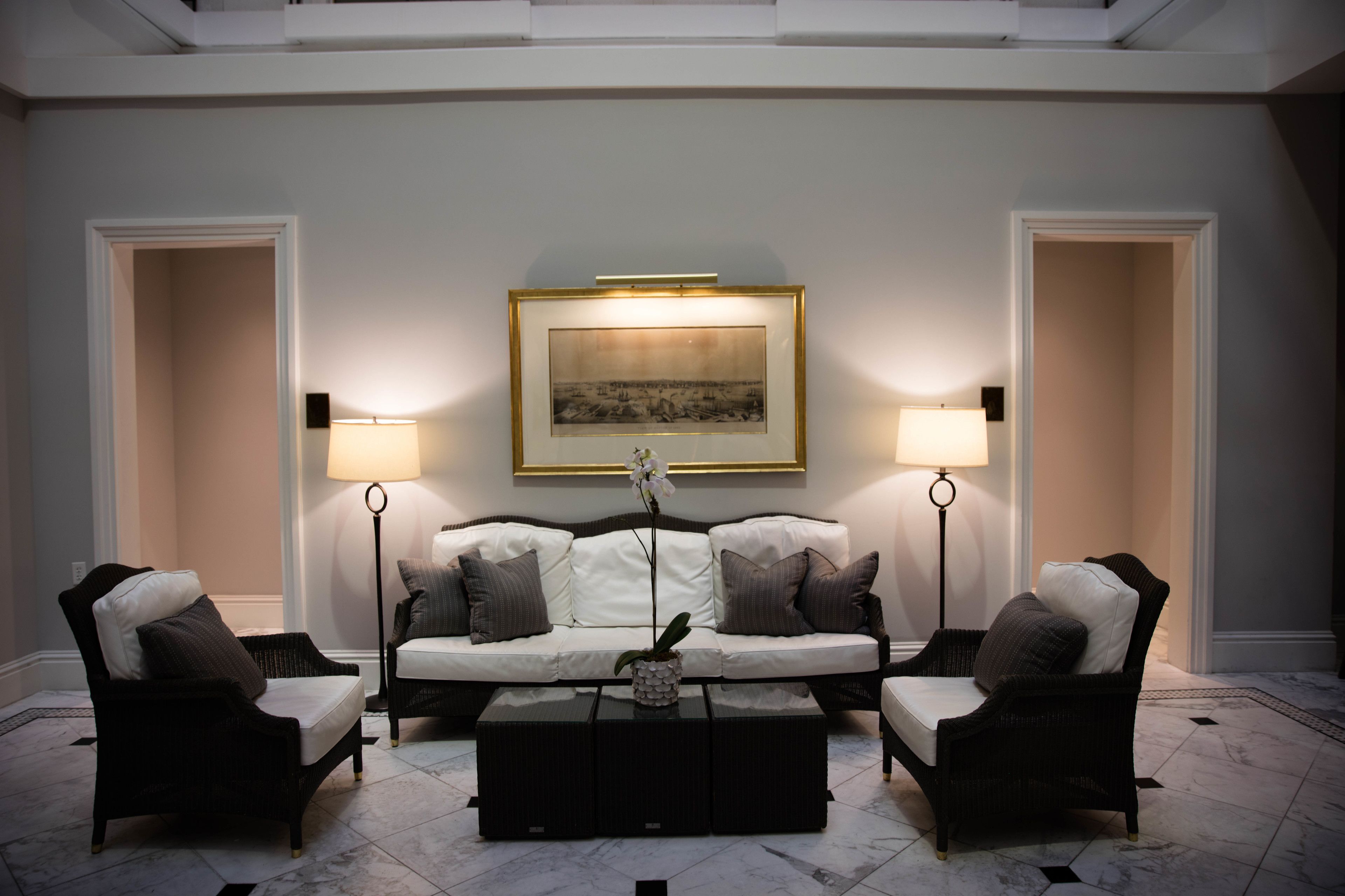 Un salon moderne avec un canapé blanc, deux fauteuils, une table basse et deux lampadaires.