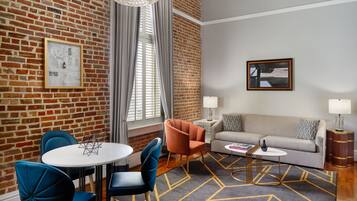 A modern living room with a brick wall, a round table with chairs, a sofa, and a patterned rug.