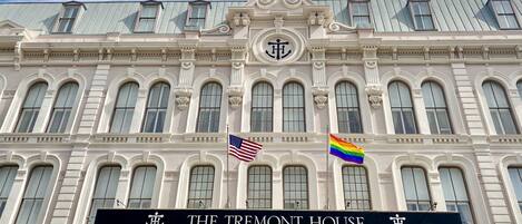 The Tremont House with a classical facade, multiple windows, and two flags (American and rainbow) on the building.