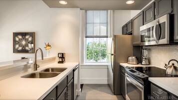 A modern kitchen with a large window, stainless steel appliances, and a minimalist design.