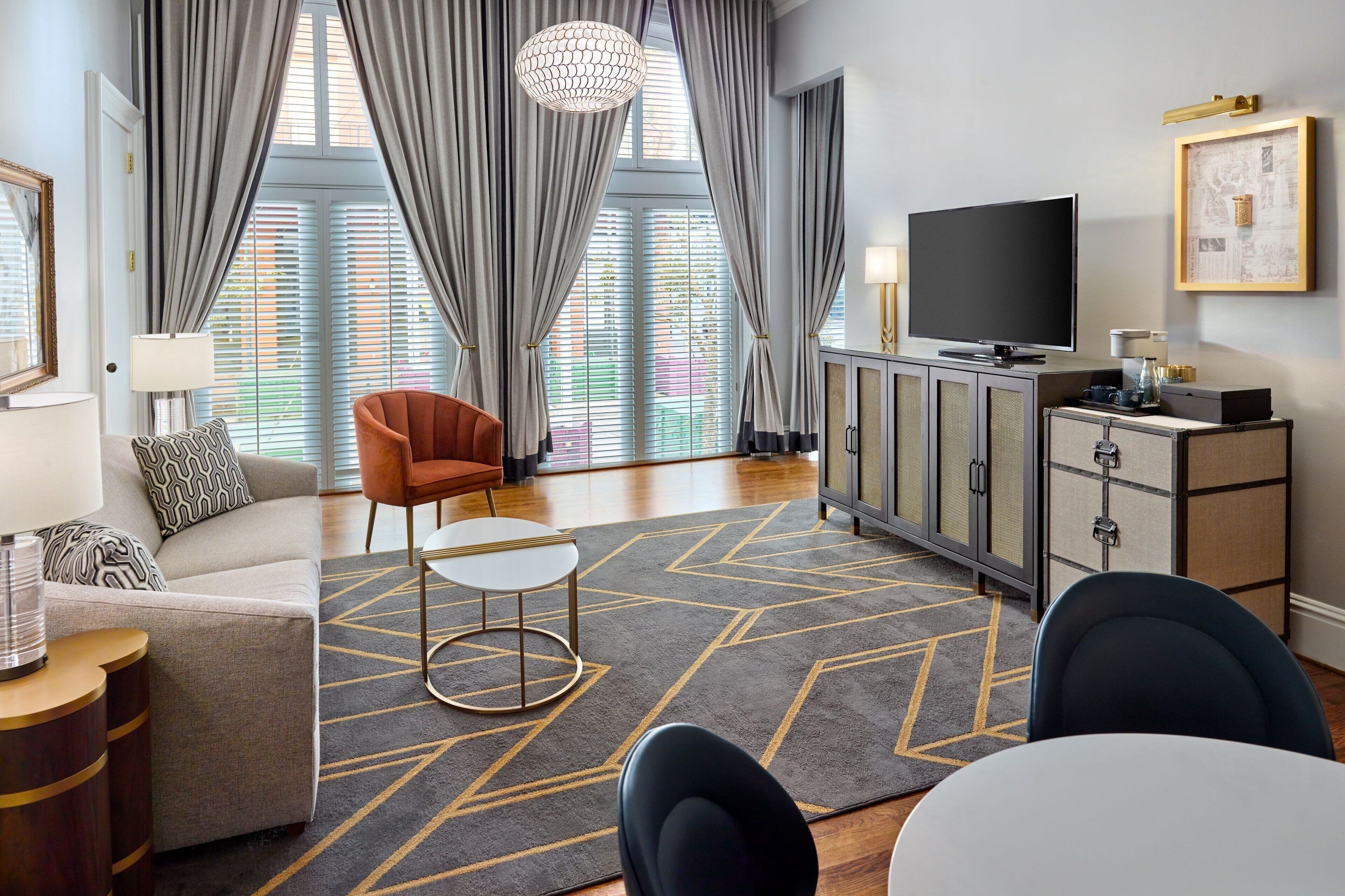 Una sala de estar moderna con un sofá, un sillón, un televisor y una alfombra geométrica.