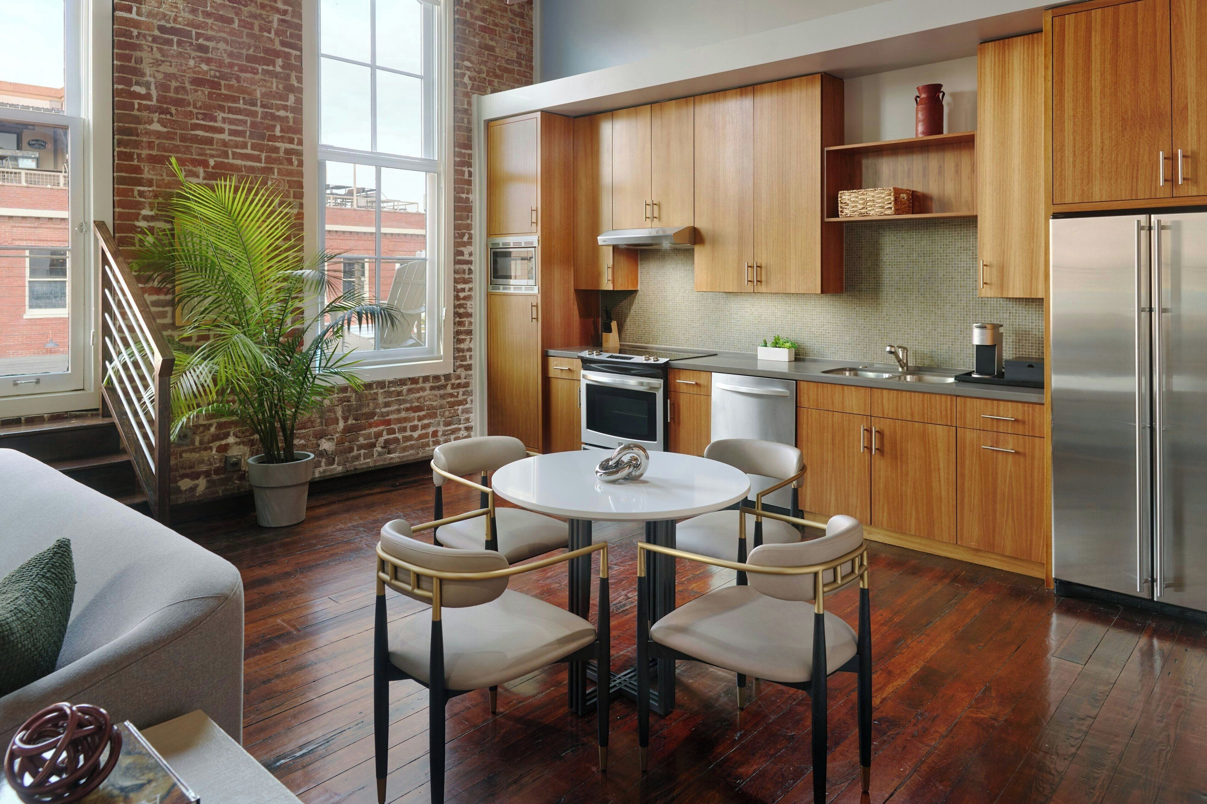 Una cocina moderna con armarios de madera, un refrigerador de acero inoxidable y una mesa de comedor redonda con sillas.