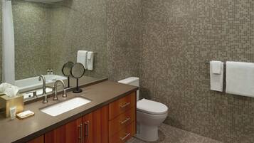 Un baño con lavamanos, espejo, inodoro y paredes de azulejos.