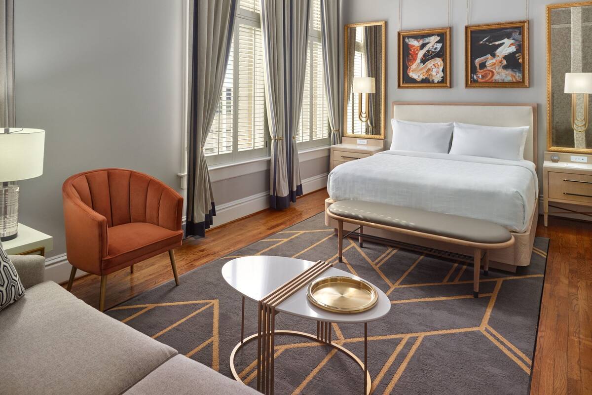 A hotel room with a bed, a chair, a small table, and a nightstand.