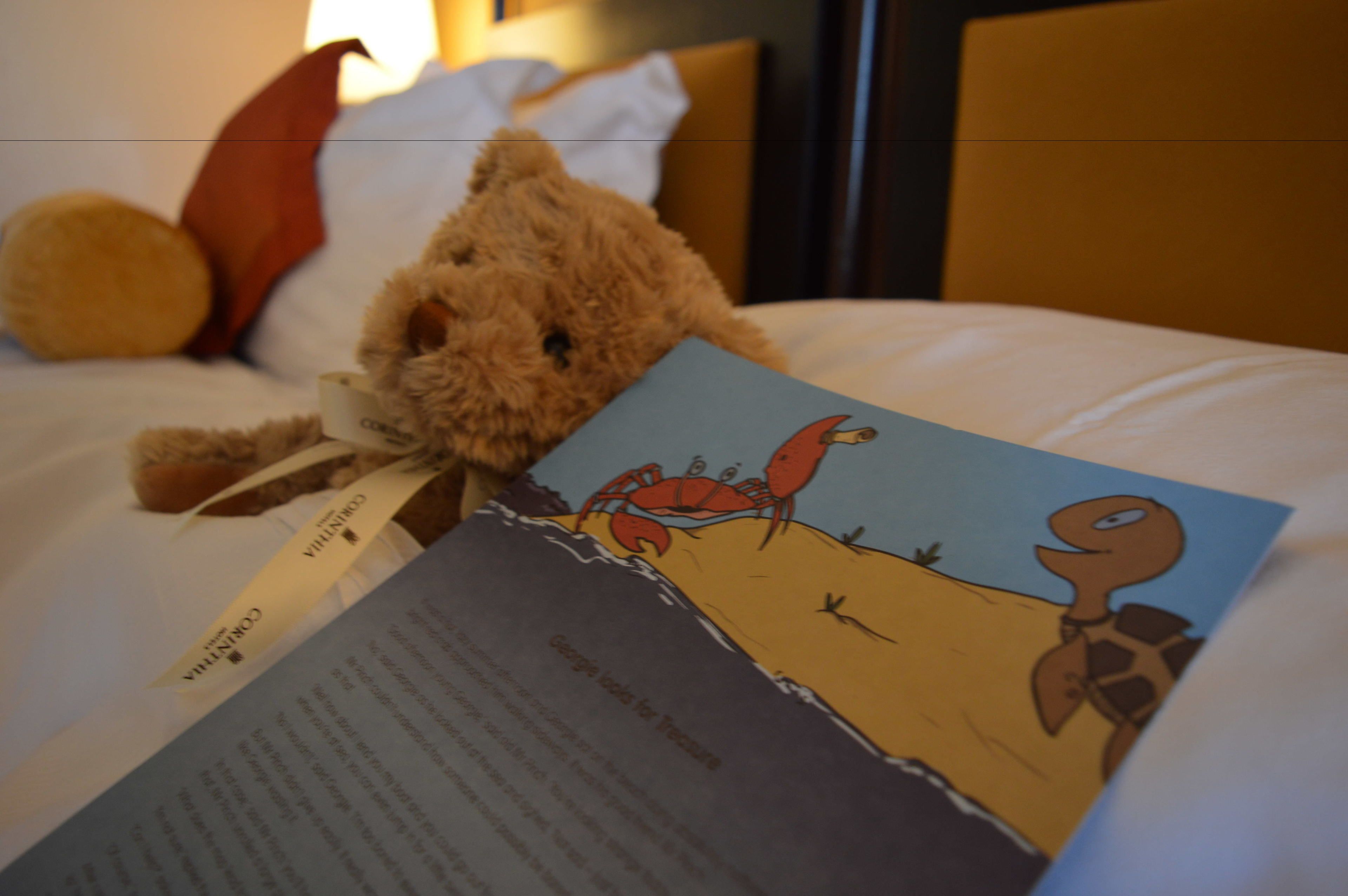 Ein Bett mit Teddybär, Buch und Kopfkissen.
