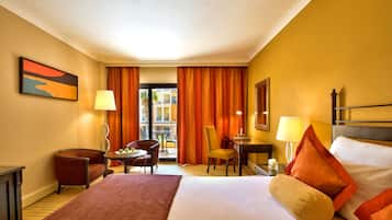 Ein Hotelzimmer mit einem Bett, einem Schreibtisch, einem Stuhl, einer Lampe und Blick ins Freie.