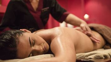 A person receiving a massage in a room with red walls and a wooden massage table.