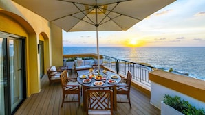A deck with a table set for dining, overlooking the sea at sunset. - Corinthia St George's Bay (St. Julian's)