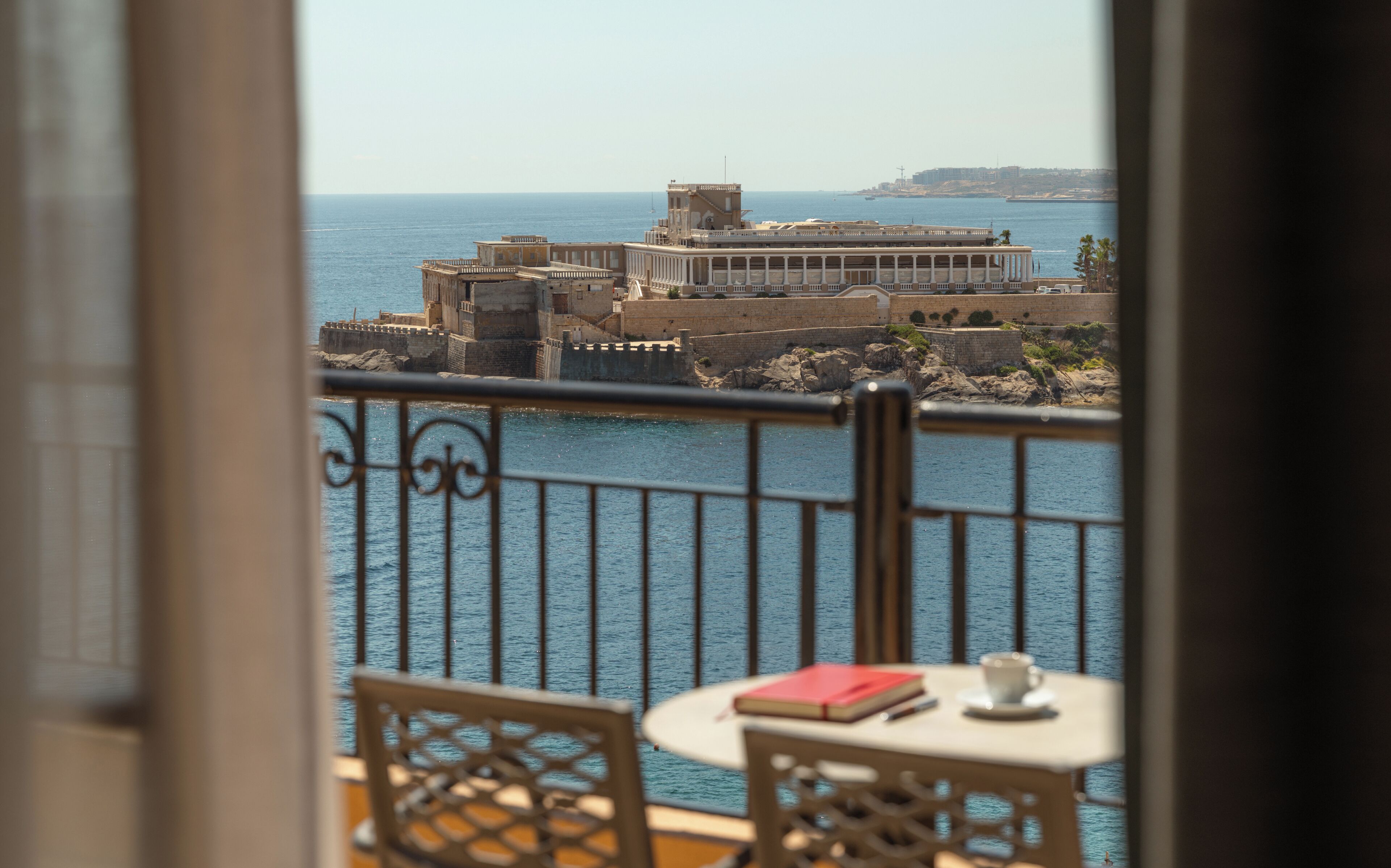 A balcony with a view of a historic building by the sea.