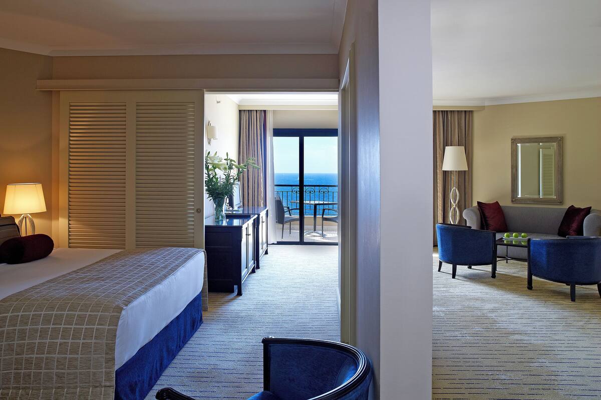 Ein Hotelzimmer mit Bett, Schreibtisch, Stuhl und Meerblick.