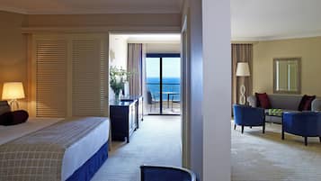 Habitación de hotel con cama, escritorio, sillón, sofá y vista al mar.