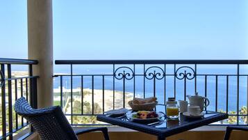 Ein Balkon mit Frühstückstisch, mit Blick auf Strand und Meer.