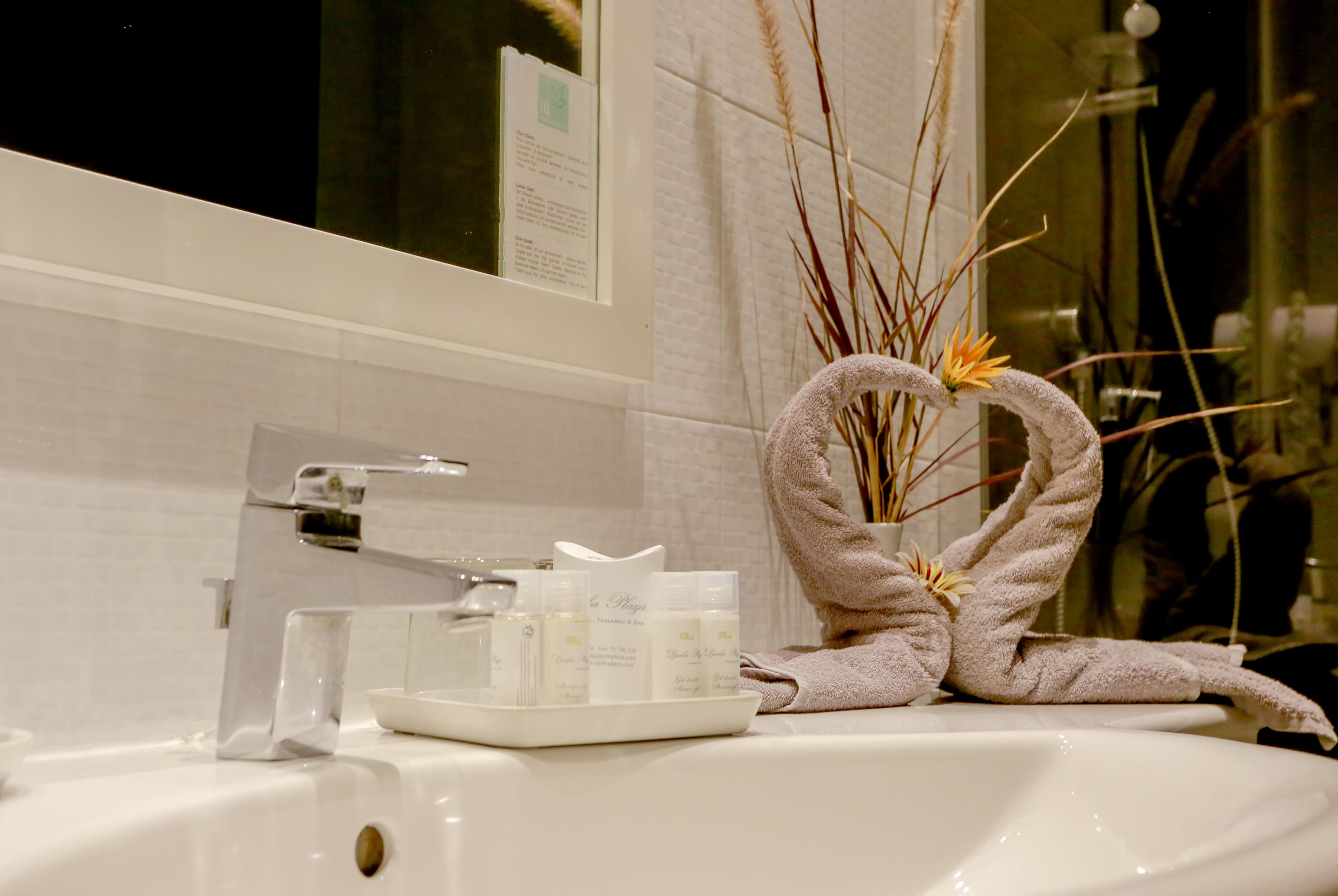 Un lavabo de salle de bain avec des articles de toilette et une serviette en forme de cœur.