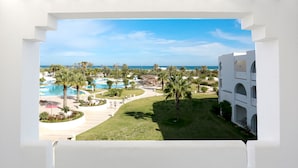 A resort view with a pool area, palm trees, and a clear blue sky. - Djerba Plaza Thalasso & Spa (Djerba Midun)