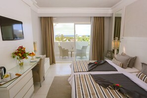 Una habitación de hotel con dos camas, un escritorio, una televisión y un balcón con vistas.