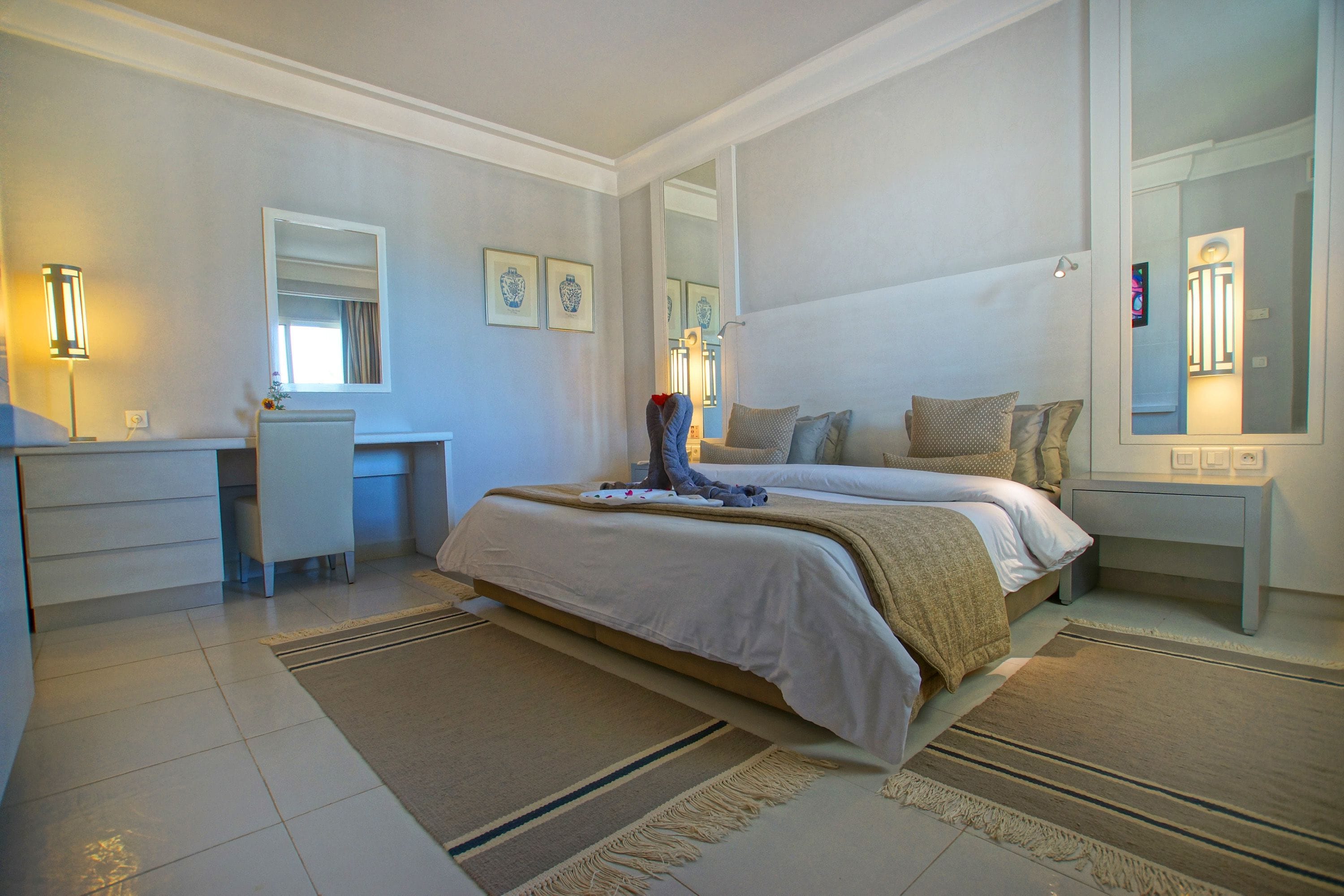 A bedroom with a bed, bedside tables, a desk, and a chair.