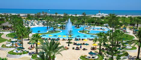 Una piscina techada, una piscina al aire libre, sombrillas