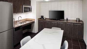 A modern kitchen with a built-in microwave, stainless steel refrigerator, and a flat-screen TV.