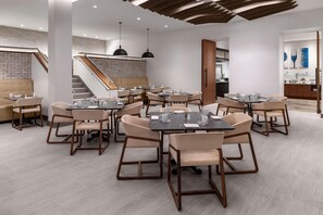 A modern restaurant with multiple dining tables and chairs, a staircase, and a buffet area. - The Bethesdan Hotel, Tapestry Collection by Hilton (Bethesda)