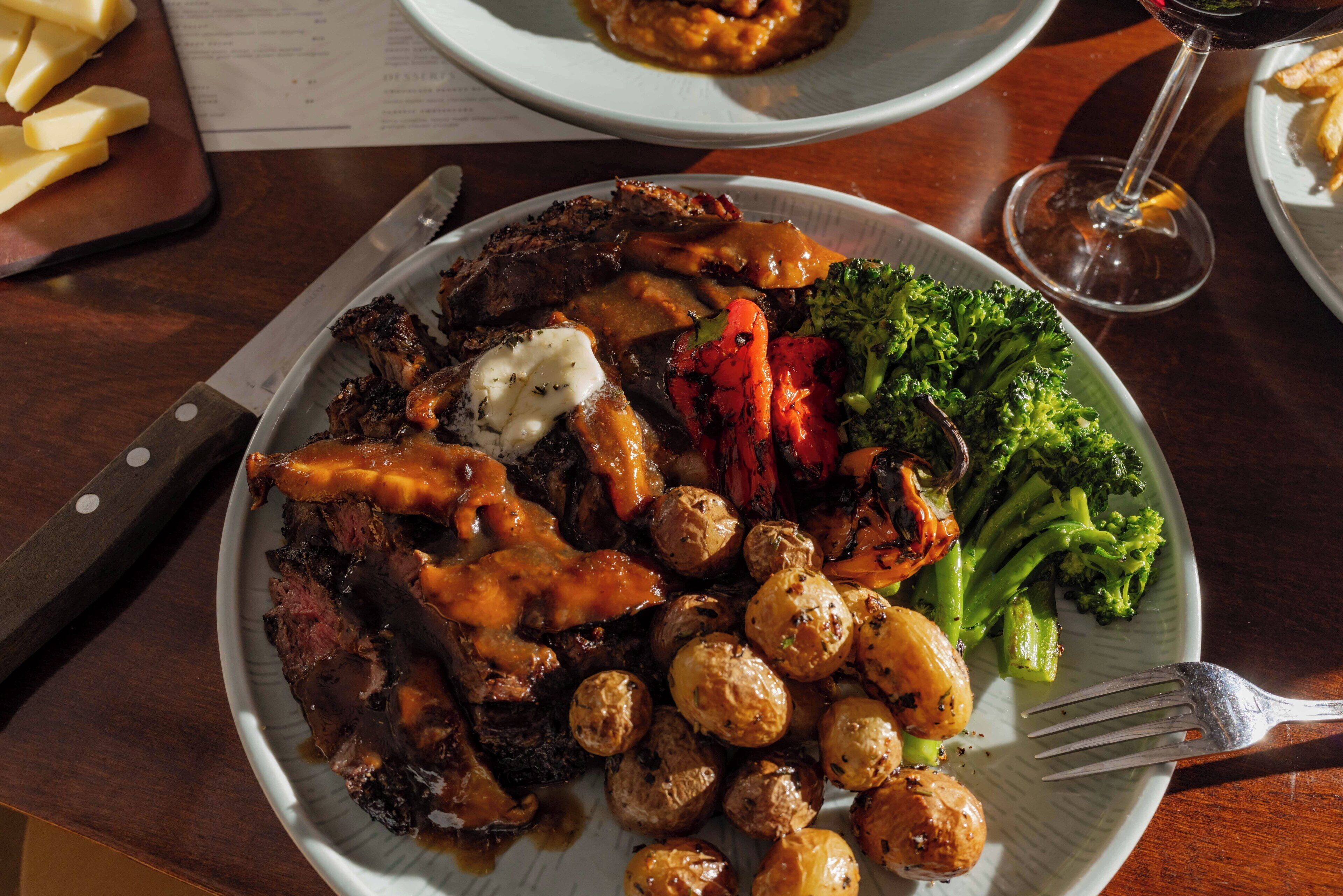 A plate of food with steak, roasted potatoes, and vegetables.