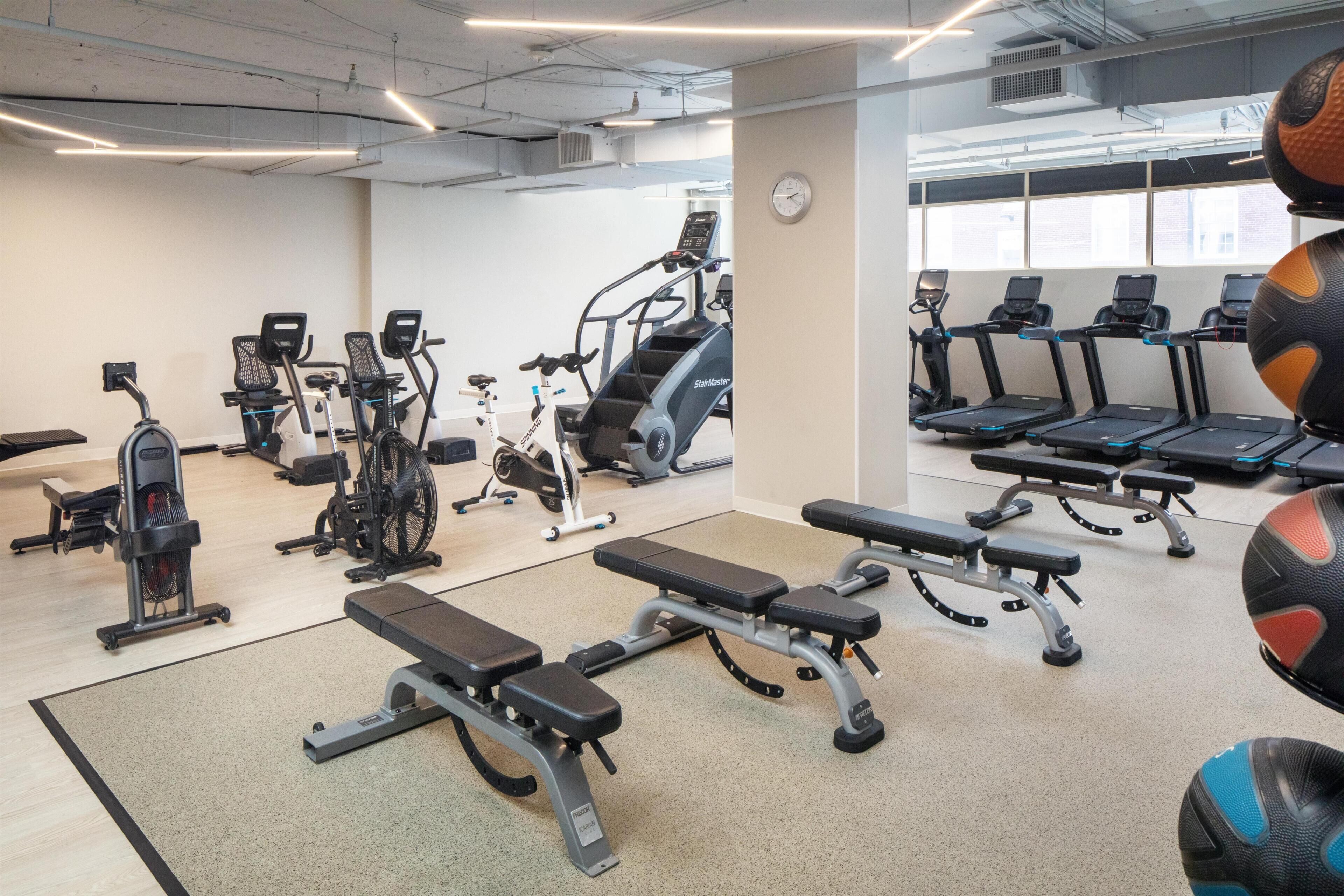 A gym with various exercise equipment, including treadmills, stationary bikes, and weight benches.