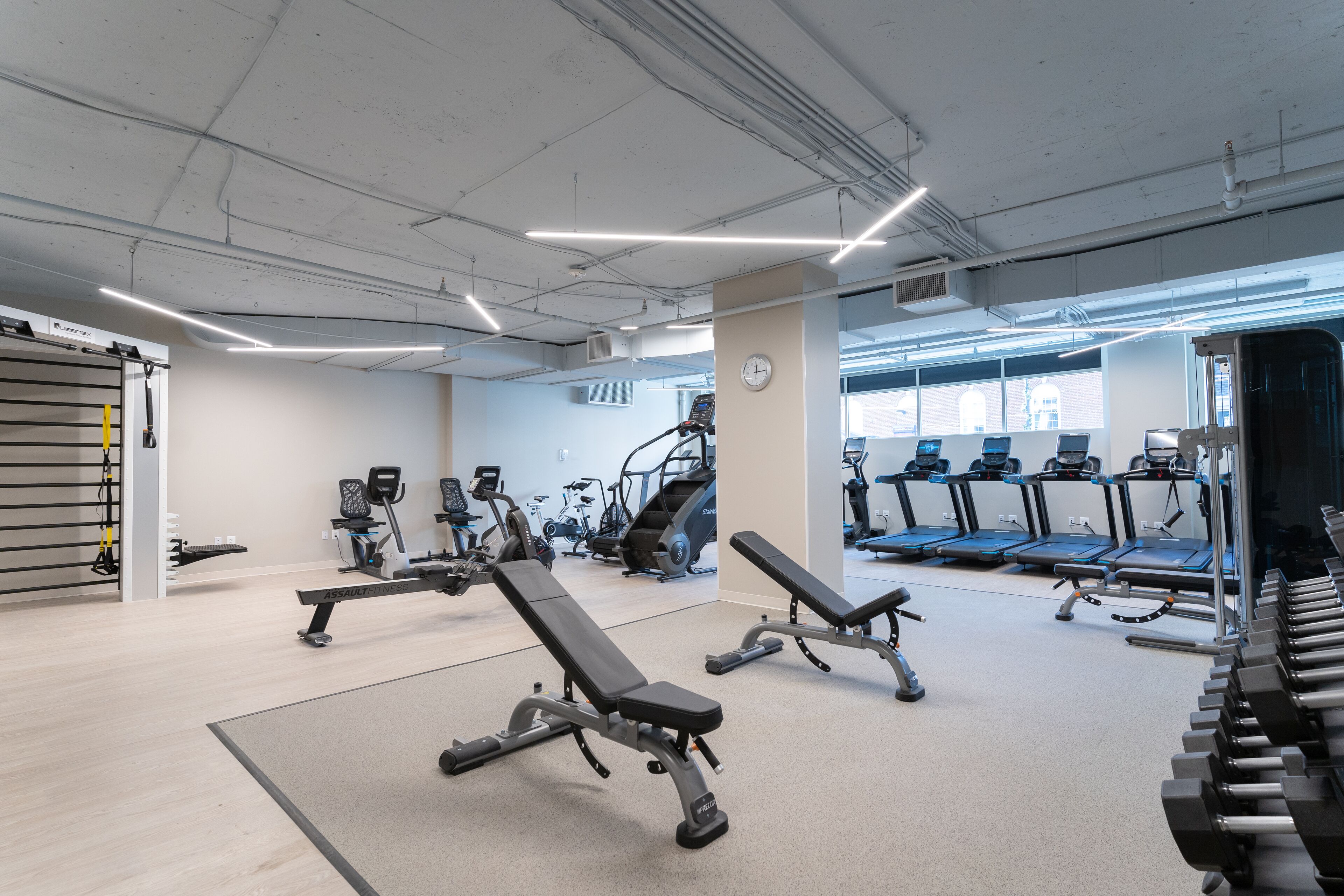 Un gimnasio con diversos equipos de ejercicio, incluyendo cintas de correr, bicicletas estáticas y máquinas de pesas.