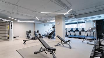 Un gimnasio con diversos equipos de ejercicio, incluyendo cintas de correr, bicicletas estáticas y máquinas de pesas.