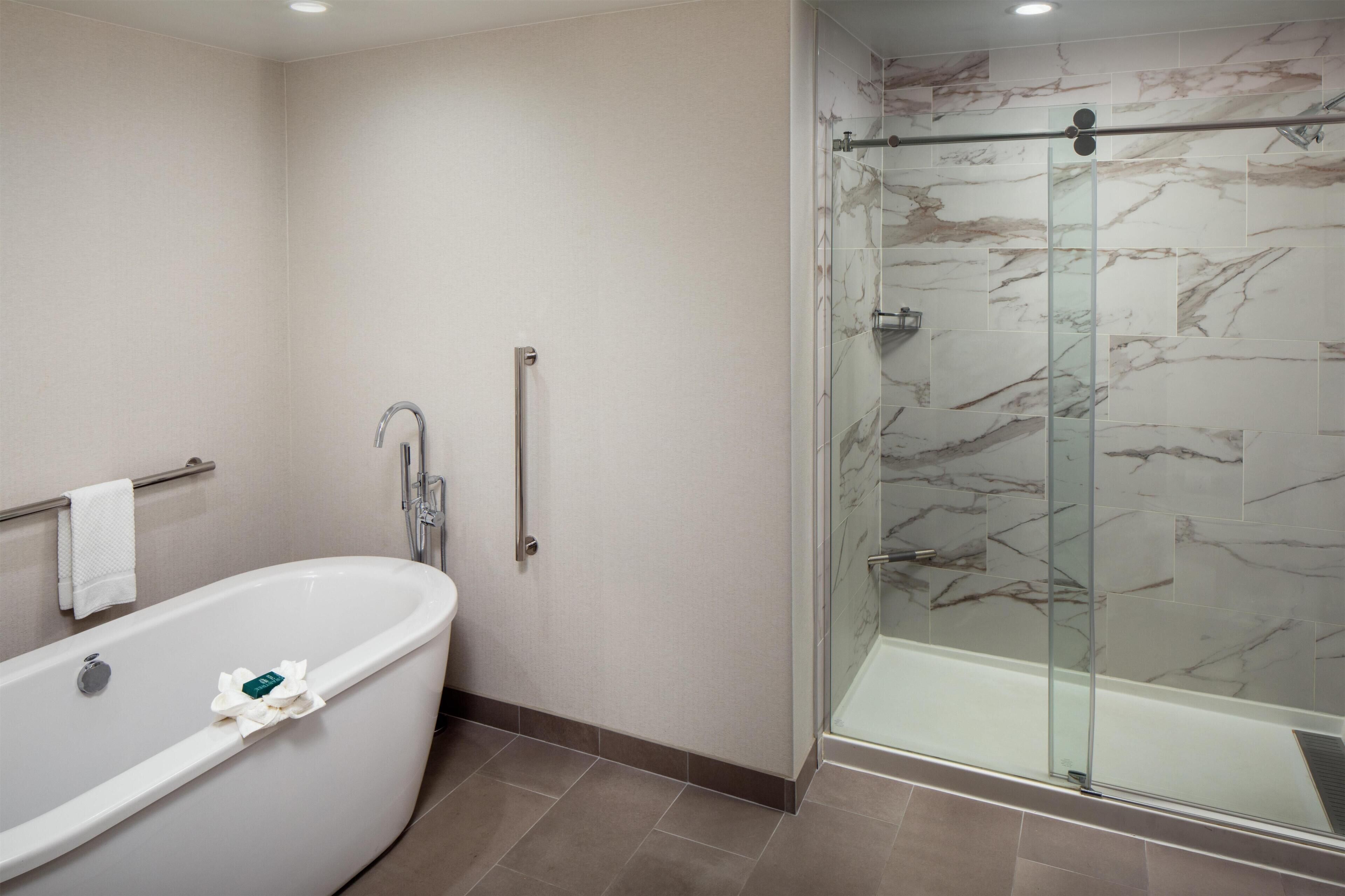 A bathroom with a freestanding bathtub, a glass shower enclosure, and a towel rack.