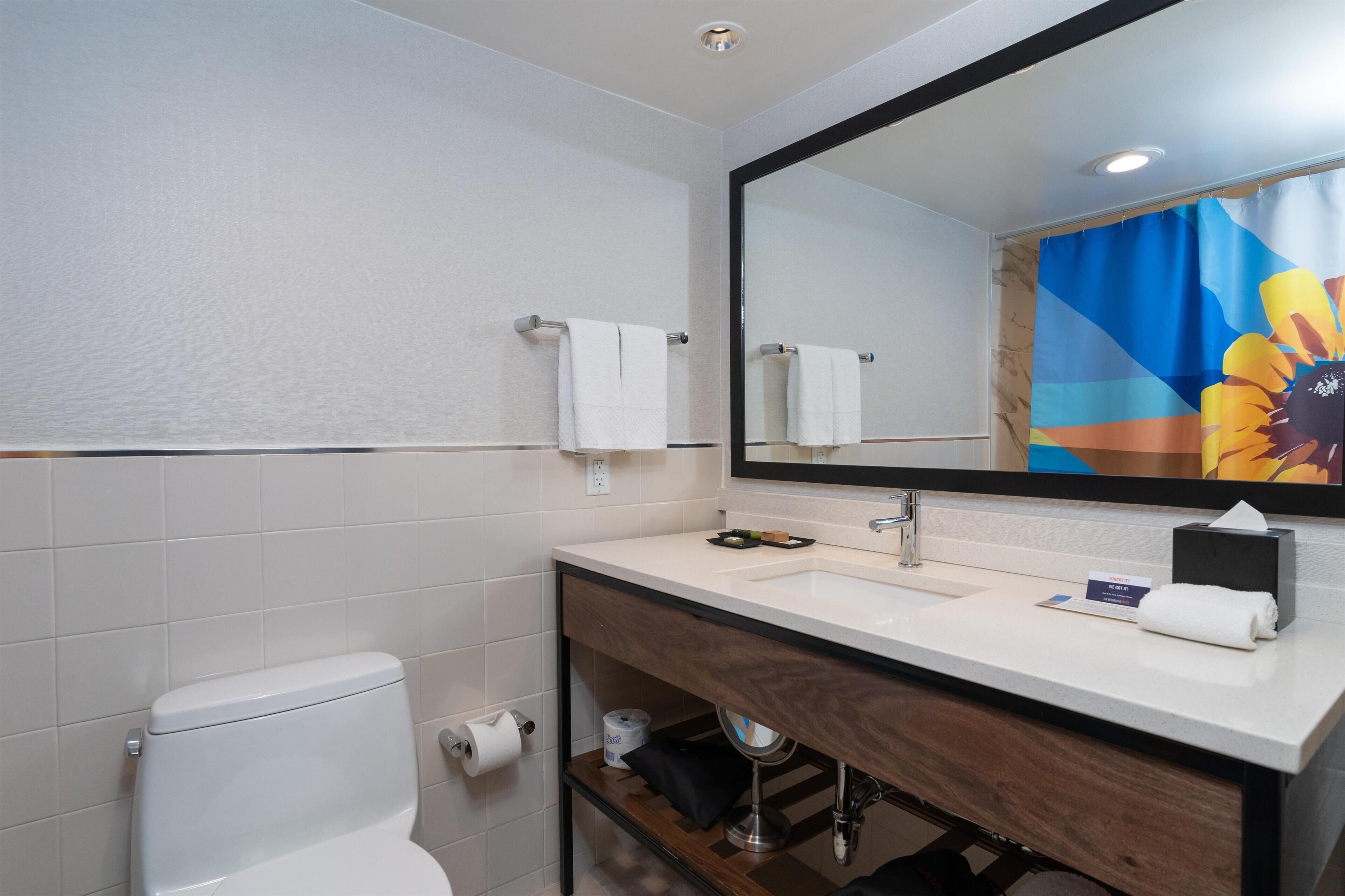 A modern bathroom with a toilet, sink, mirror, and towel rack.