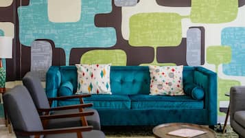 A room with a teal sofa, a round coffee table, and a patterned wall.