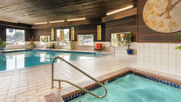 An indoor swimming pool with tiled flooring, a metal ladder, and a large wall clock. - Best Western Prineville Inn (Prineville)
