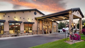 A hotel entrance with a covered driveway, stone facade, and outdoor seating area. - Best Western Prineville Inn (Prineville)