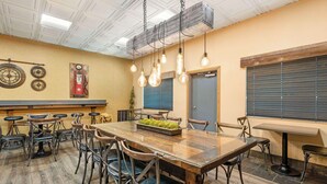 A conference room with a large wooden table, multiple chairs, hanging light fixtures, and a clock on the wall. - Best Western Prineville Inn (Prineville)