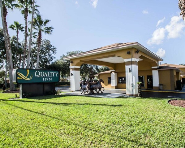 Un hôtel Quality Inn doté d’une entrée couverte, de palmiers et d’une enseigne.