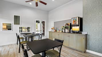 A dining area with a table and chairs, a kitchen with cabinets, a ceiling fan, and framed artwork on the walls.