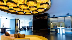 Un vestíbul modern amb una zona d'estar central, una taquilla d'adreça i un lluminari circular gran.