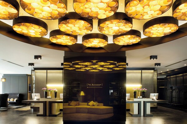 Relax in the hotel's inviting lobby, featuring a curved sofa and a small table with a lamp.