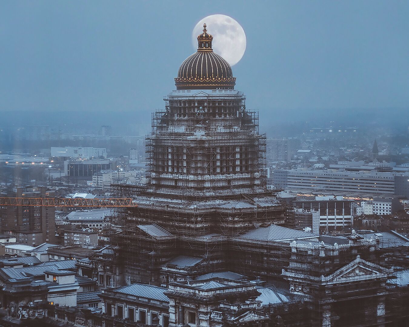 Um edifício grande, com vários níveis, uma cúpula imponente e uma lua cheia ao fundo.