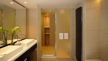 Een moderne badkamer met een dubbele wastafel, een douchecabine van glas en een spiegel met een bloevas.