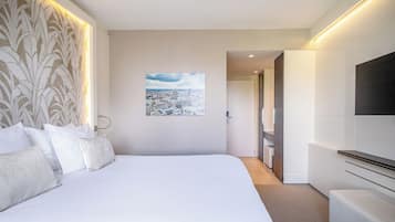 Un hotel moderno con una cama grande, vistas a la ciudad, un televisor de pantalla plana y un vestidor.