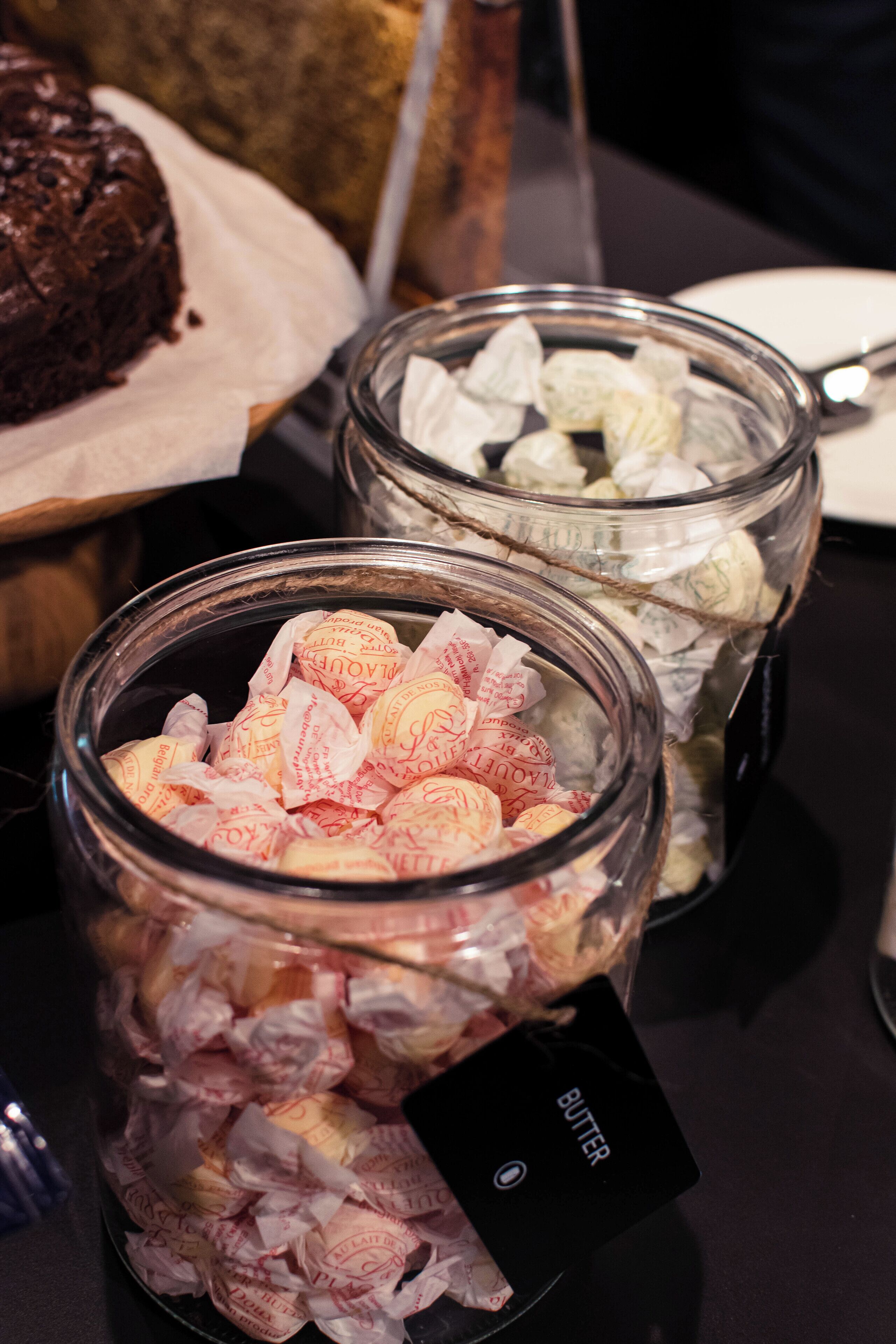 Two glass jars filled with wrapped candies, one labeled "BUTTER" and the other with a different label.