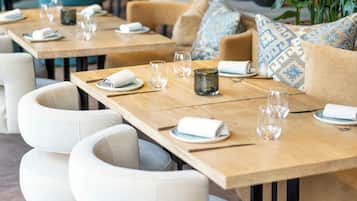 Un restaurante con largas mesas de madera, sillas blancas acolchadas y una decoración interior moderna.