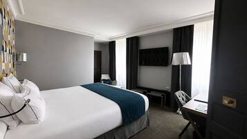 Una habitación de hotel con una cama grande, un escritorio, una silla, un televisor y una puerta.