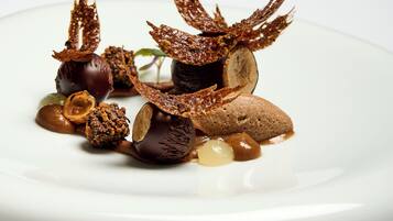 Un postre sobre un plato blanco con distintos elementos y adornos de chocolate.