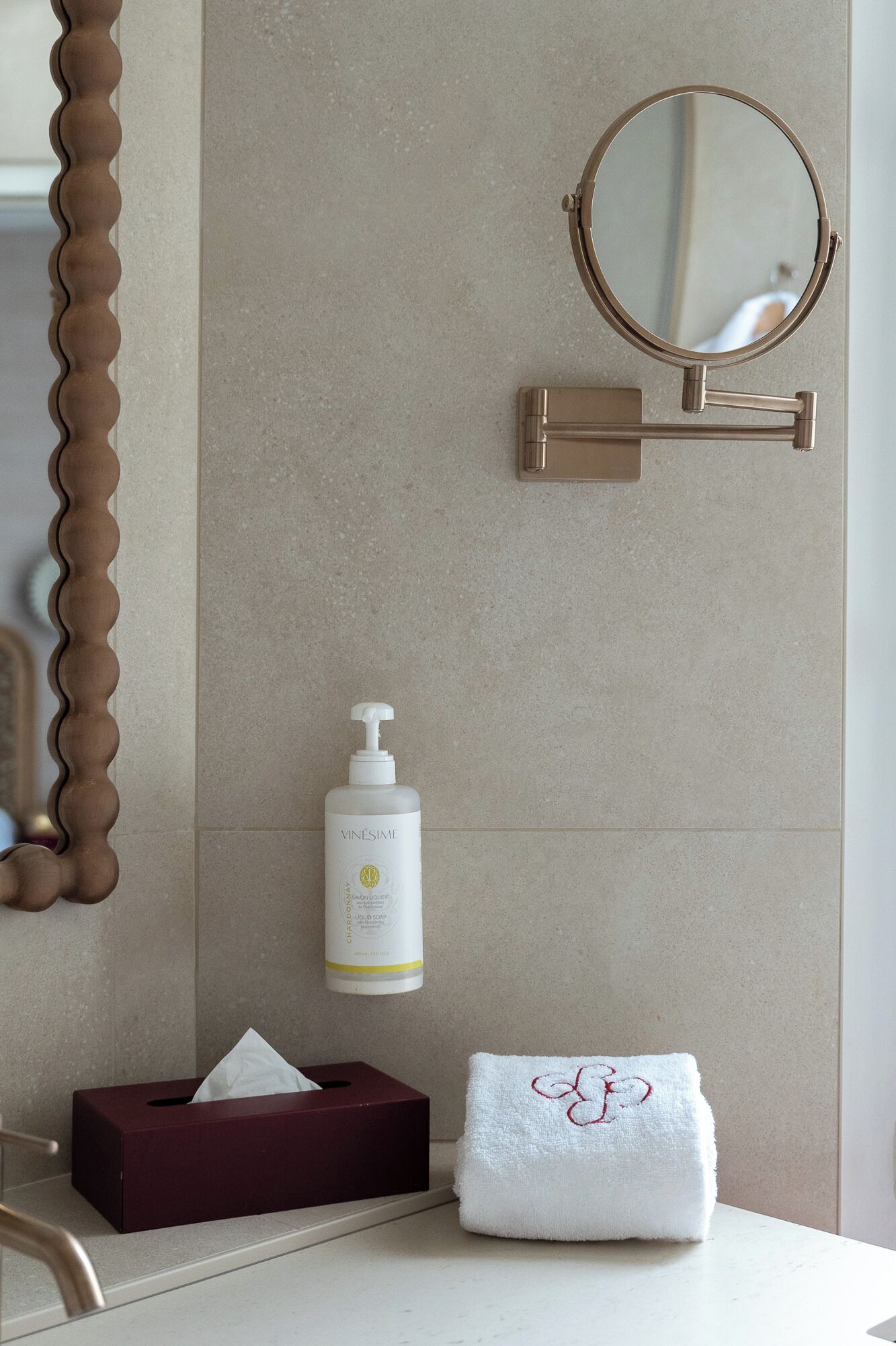 Une salle de bain équipée d’un miroir, d’un distributeur de savon, d’une boîte de mouchoirs et d’une serviette.