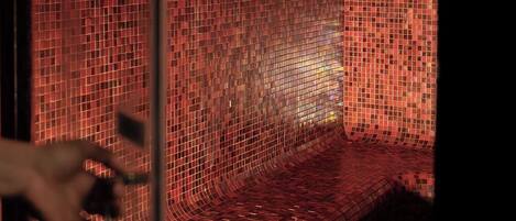 A tiled wall with a hand reaching towards it.