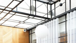 A modern room with a glass ceiling, a sofa, two armchairs, a coffee table, and a decorative vase.