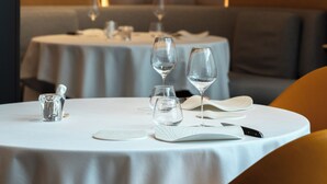 A restaurant with round tables, white tablecloths, and a warm ambient light.