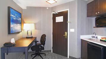Ein Hotelzimmer mit Schreibtisch, Stuhl, Lampe, Telefon und einer Mikrowelle.